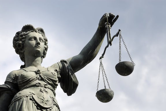 Statue der Justitia mit Waage vor Himmel