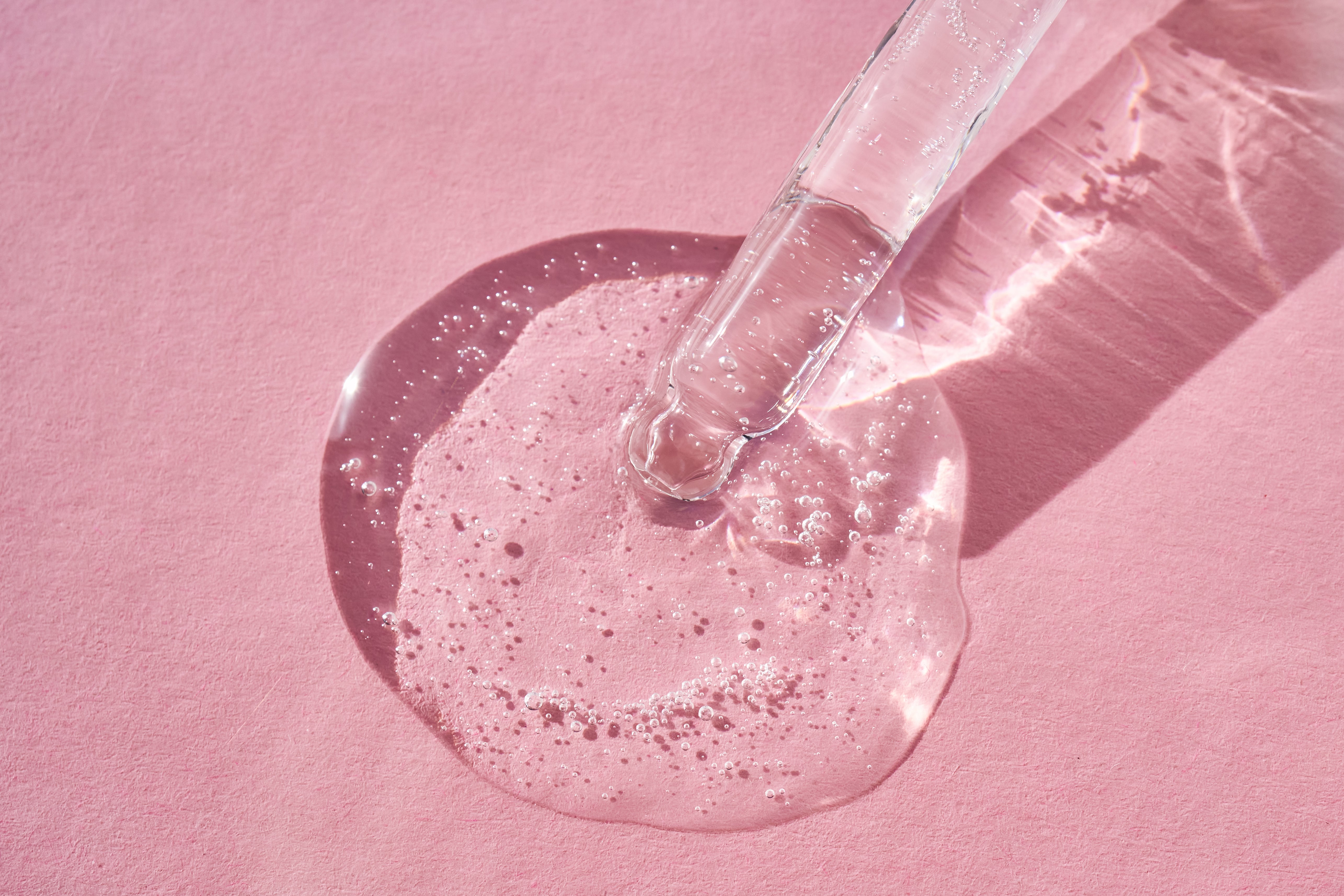 klares Serum auf einem pinken Hintergrund
