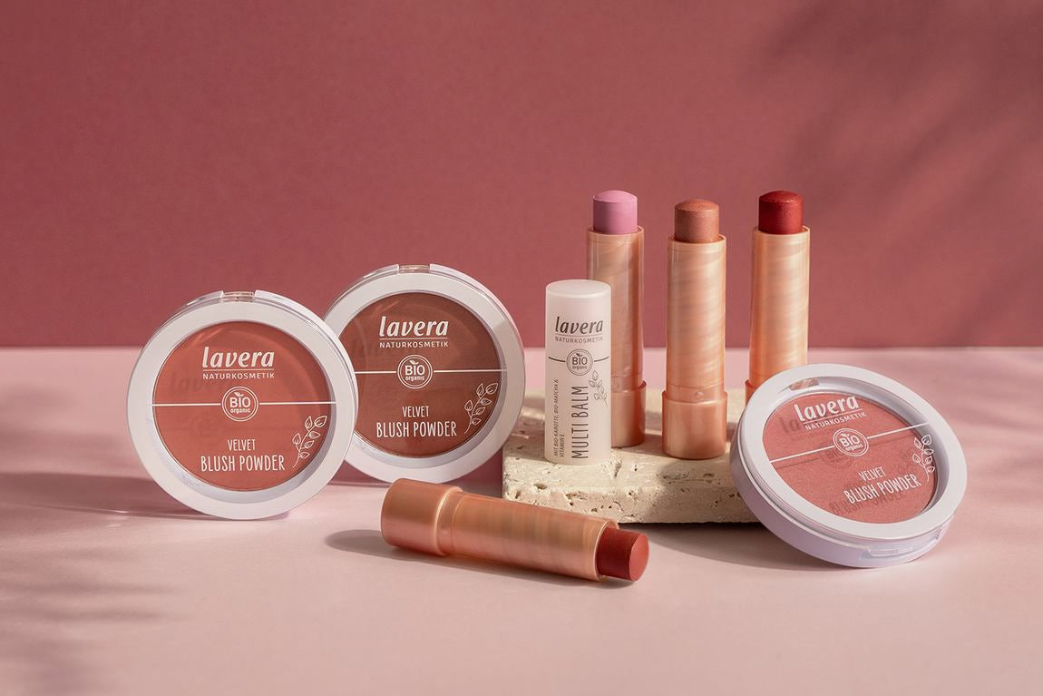 Lavera Rouge-Sortiment mit Blush Powdern und Multi Balms auf rosa Fläche