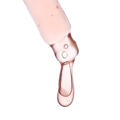 pipette nahaufnahme mit hell rosa farbener Flüssigkeit und Tropfen vor weißem Hintergrund